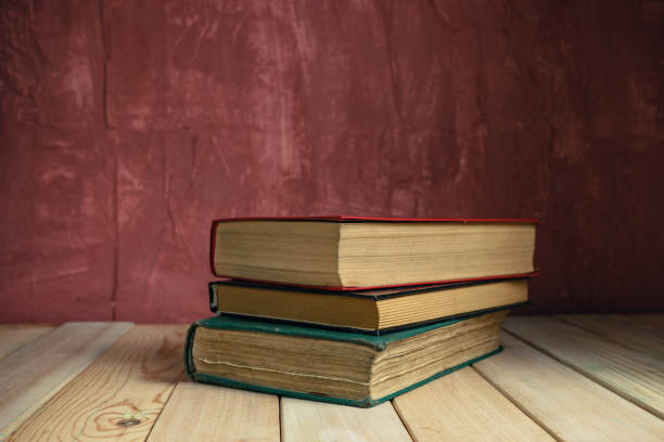 istock Old books on a old wooden table. Beautiful Red wall background. 1258126245