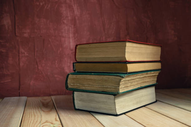 istock Old books on a old wooden table. Beautiful Red wall background. 1258126257