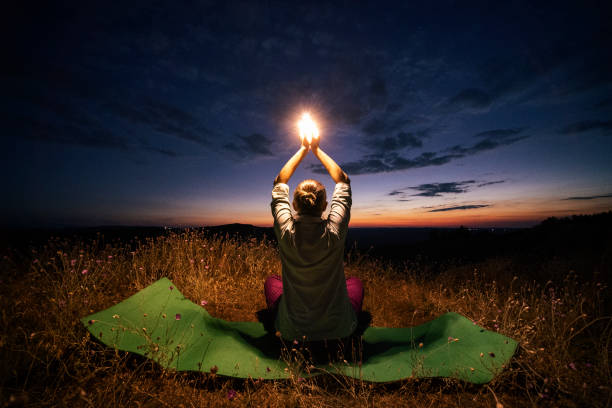 Relax and go Back to Nature. Yoga at night. Solo traveler. WS of a Cheerful Young Woman Tourist Doing Relaxation Exercises in the Nature. A Cheerful Adult tourist meditating in the Nature. Relaxation Outdoors at the end of the day. Casual Clothing. Weekend Activities. spiritual enlightenment stock pictures, royalty-free photos & images