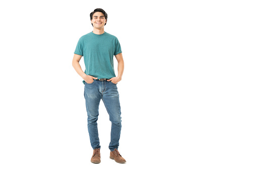 Smiling good looking young man standing with hands in pockets of denim jeans