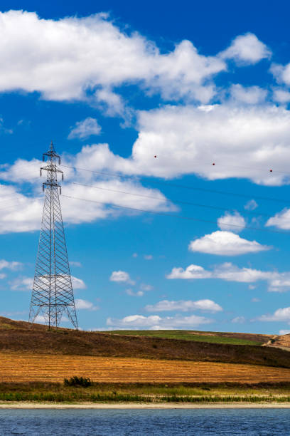 High voltage transformer line pylons on agricultural land by the lake in Turkey.