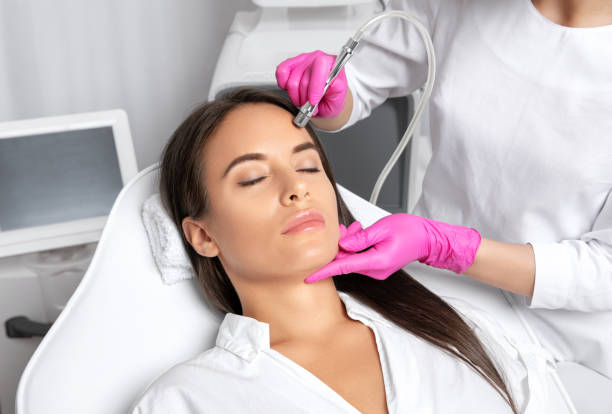 Beautiful woman with long hair, with clean fresh skin.Cosmetologist makes  procedure microdermabrasion on the face. Women's cosmetology in the beauty salon. Beautiful woman with long hair, with clean fresh skin.Cosmetologist makes  procedure microdermabrasion on the face. Women's cosmetology in the beauty salon. microdermabrasion stock pictures, royalty-free photos & images