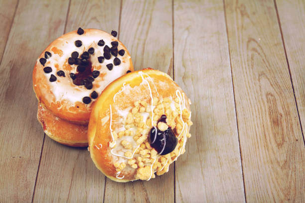 istock Delicious glazed doughnuts on wooden table 1258129527