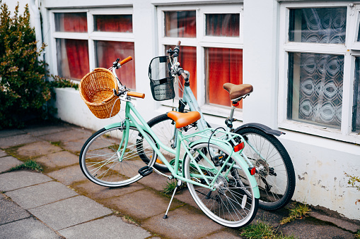 Two bicycles with grocery baskets by an old house with large windows. High quality photo
