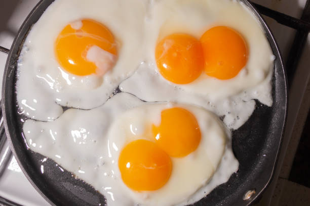istock Simple rustic fried eggs in a frying pan top view. Eggs with two yolks. View through steam. 1258137657
