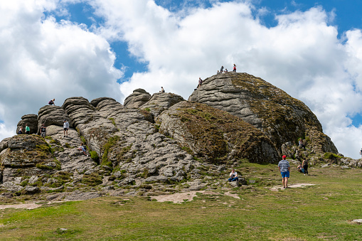 Haytor, near the B3387 . This is on South Dartmoor, Cornwall, England, UK. There are people climbing on the rock formation.