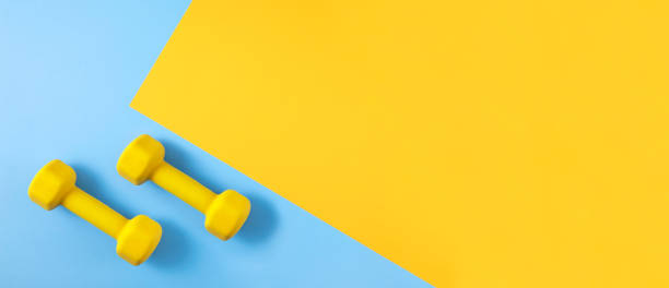 istock Dumbbells on Blue and Yellow Background 1258141656