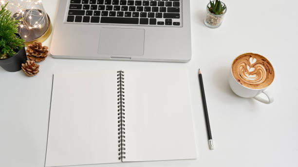 istock Cropped shot view of modern workspace with computer, notebook , pencil, coffee cup and lightbulb on white table in home office. 1258141909