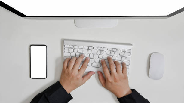 istock Top view of businessman using computer on white table in home office with blank screen smartphone. 1258141921