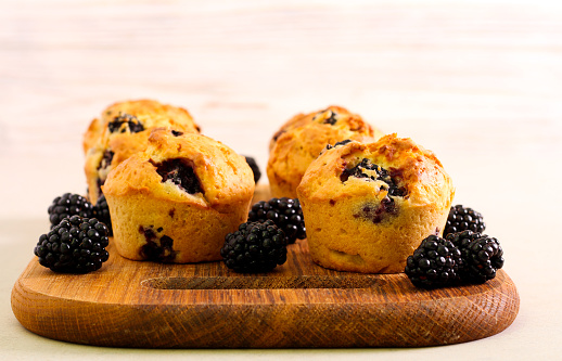 Sweet blackberry muffins on wooden board