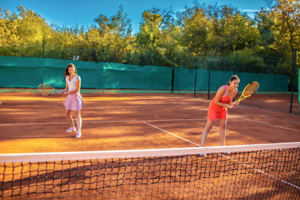 istock Young female friends playing doubles tennis 1258149708
