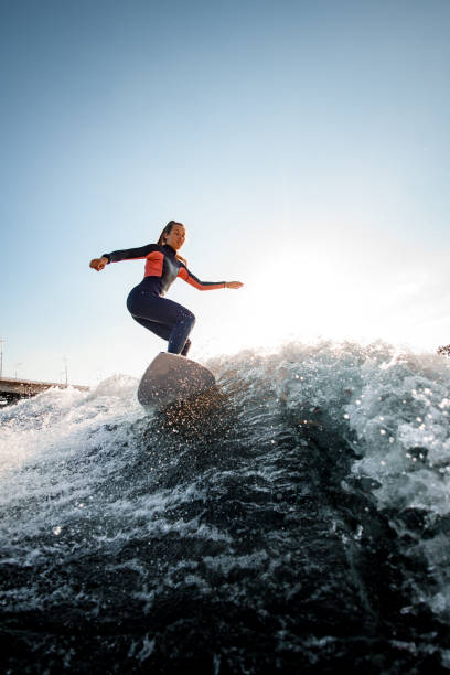istock young woman in a wetsuit on surfboard rides the wave. 1258151421
