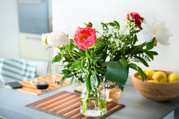 Peonies bouquet in glass vase on home kitchen interior background. modern apartment decor, household lifestyle