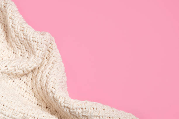 istock Cozy knitted beige blanket or sweater on pastel pink background 1258156193