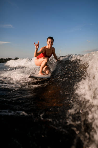 istock smiling woman rides on surfboard and shows hand gesture 1258161844