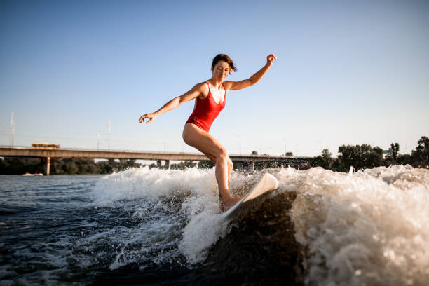 istock active woman masterfully rides the wave on surfboard 1258164483
