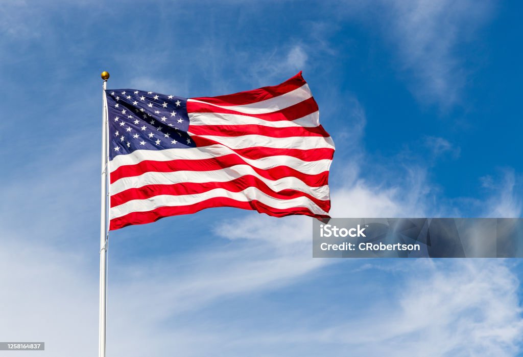 鮮豔的美國國旗在風中飄揚,鮮豔的紅白藍兩色被太陽照耀,與藍天對著複製空間。 - 免版稅美國國旗圖庫照片