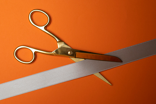 Golden scissors cutting a ribbon.
