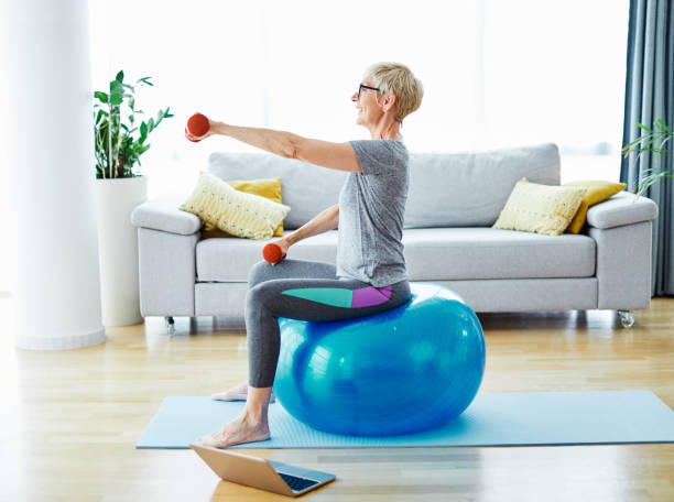 senior exercice intérieur femme formation style de vie sport fitness à la maison gym saine exercice ordinateur portable ajustement - yoga ball photos et images de collection