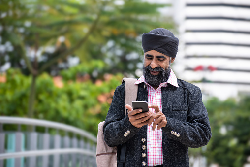 Bearded Silk businessman with turban using smart phone and on the way to work