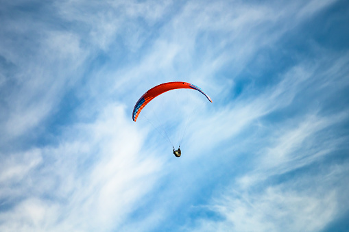 Photo of a man gliding in the sky on a parachute.