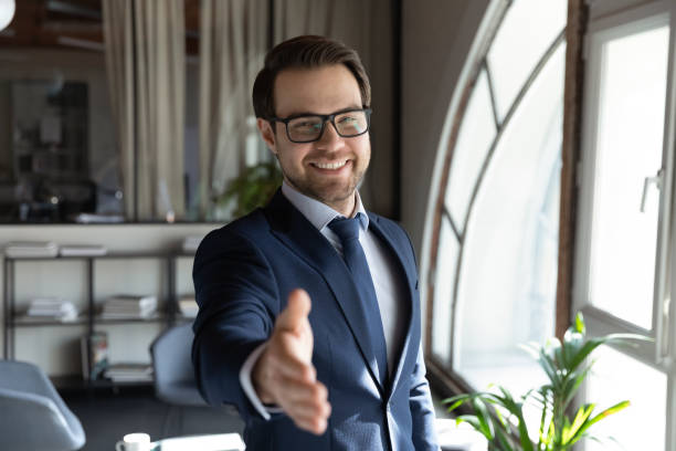 retrato de la reunión de mano de estiramiento de hombre de negocios sonriente con el cliente - business looking at camera office new fotografías e imágenes de stock