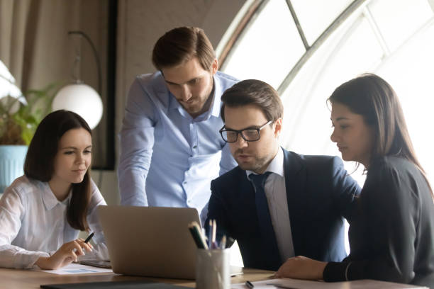 istock Focused multiethnic colleagues work on laptop in office together 1258168141
