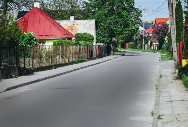 Asphalt road across village next to fences and houses