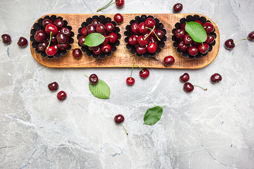 Flat lay composition with sweet cherries on marble table, space for text.