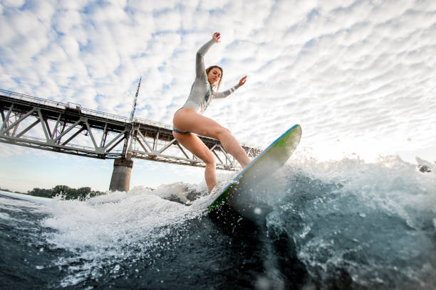 istock blonde woman balanced on wave on surfboard 1258170100