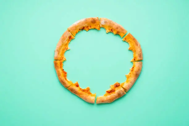 Photo of Pizza crust only isolated on a green background. Pizza leftovers top view.