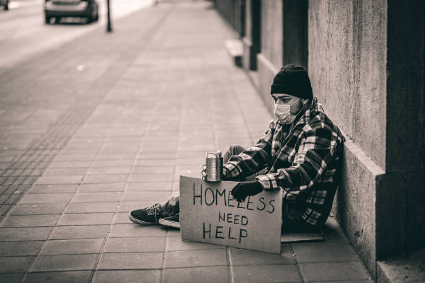 istock Homeless man sitting outdoors and holding cardboard 1258172807