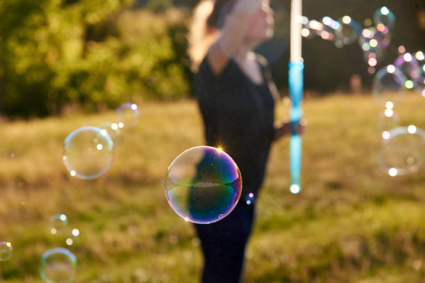 istock Woman blowing soap bubbles on the meadow in summer. 1258179701