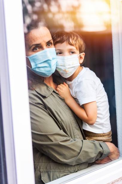 istock Mature woman posing with her son, both with protective masks, very sad looking through window worried about loss of her job due Covid-19 pandemi 1258188045