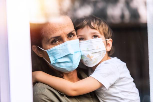 istock Mature woman posing with her son, both with protective masks, very sad looking through window worried about loss of her job due Covid-19 pandemi 1258205815