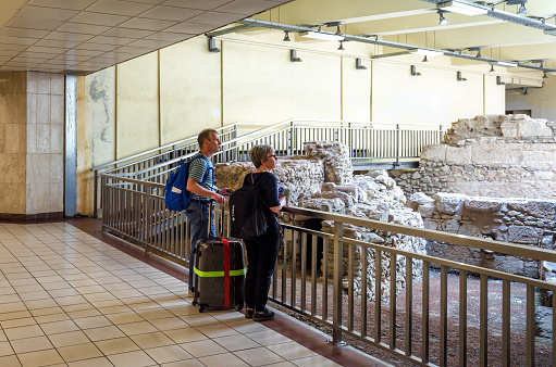 Athens - May 9, 2018: Tourists look at Ancient ruins inside Monastirion (Monastiraki) metro station in Athens city center, Greece. Subway interior with remains of classical Greek buildings.