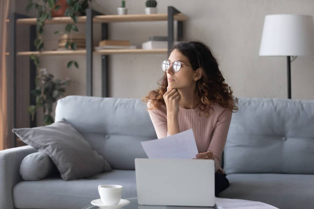 istock Pensive young woman distracted from work dreaming at home 1258279537
