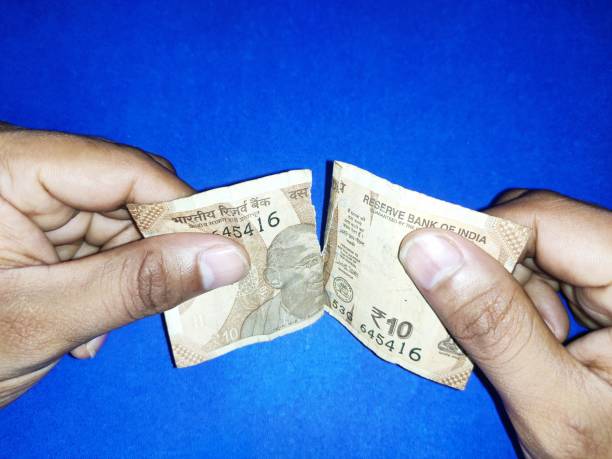 istock Torn Ten rupees Indian note in hand on blue background note in hand on blue background 1258305028