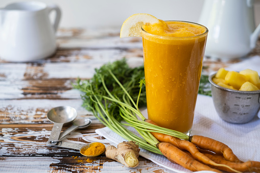 A glass of carrot juice on a dark wooden background. Flat lay.