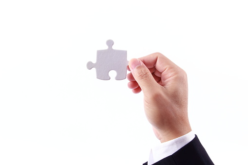 Business man hand holding a pieces of jigsaw puzzle, isolated on white background