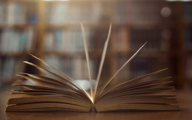 istock Old open book on the table a bookshelf background for academic education learning concept. 1258458700