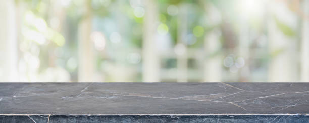 istock Empty black stone marble table top and blurred of interior restaurant with window view green from tree garden background background - can used for display or montage your products. 1258462762