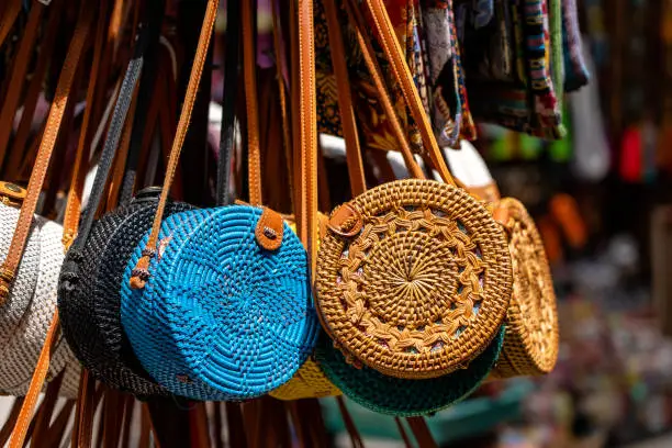 Photo of Famous Balinese rattan eco bags in a local souvenir market on street in Ubud, Bali, Indonesia. Handicrafts and souvenir shop display