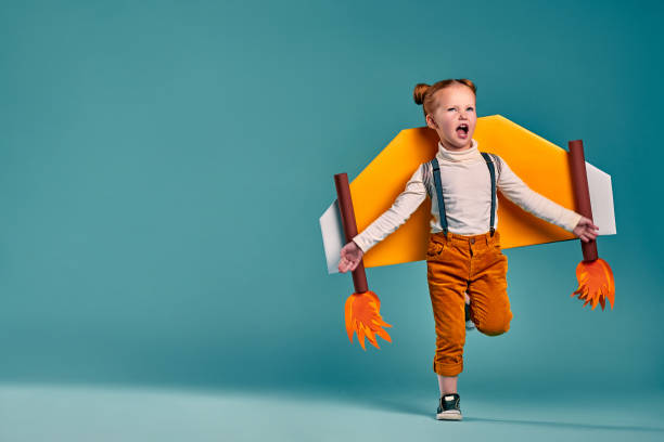 little child playing pilot. happy child playing with toy wings against blue background - toy spaceship inspiration ideas imagens e fotografias de stock