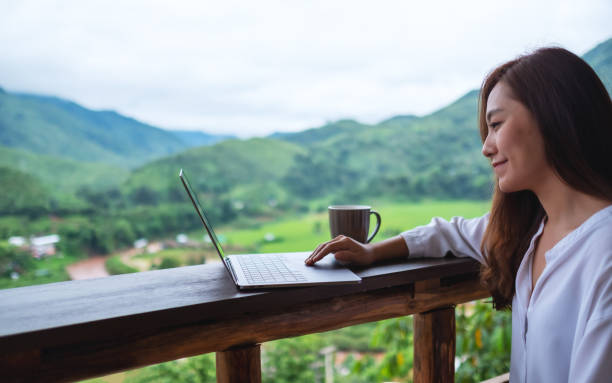 istock A beautiful asian woman working and typing on laptop computer while sitting on balcony with mountains and green nature 1258530672