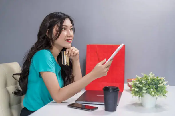 woman thiking and using digital tablet for online shopping with a credit card