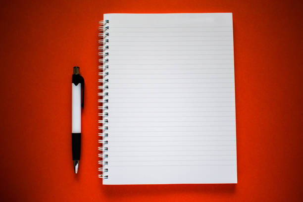 istock Notepad with black and white pen on orange background 1258583628
