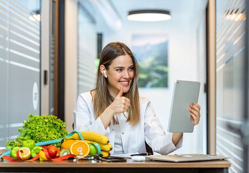 Female dietician making thumbs up sign to her client