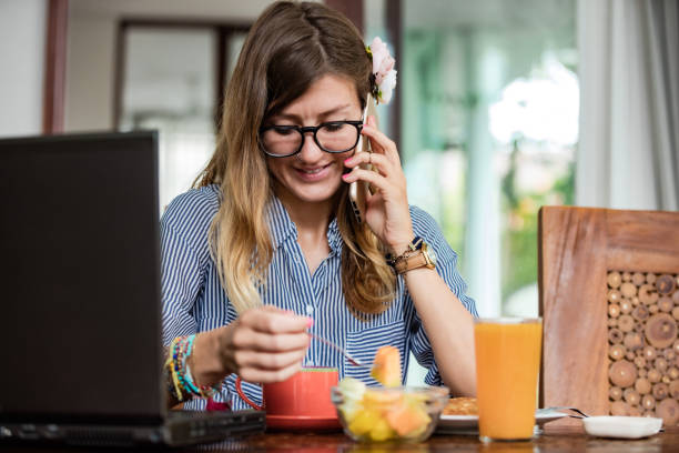 istock Woman using laptop and cellphone at home during breakfast - freelancing concept. 1258584686