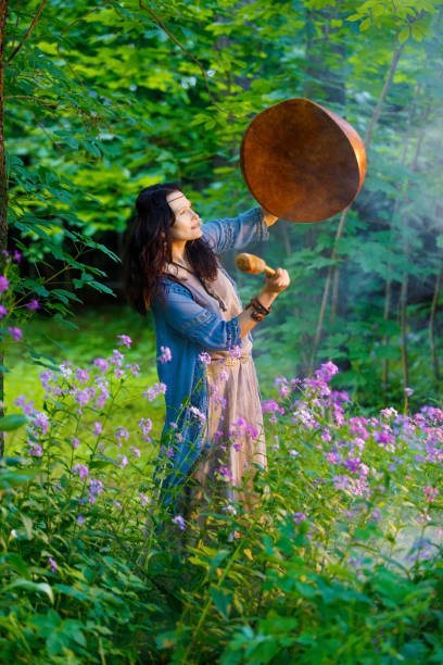 Shaman woman performs a ritual with a tambourine in the forest